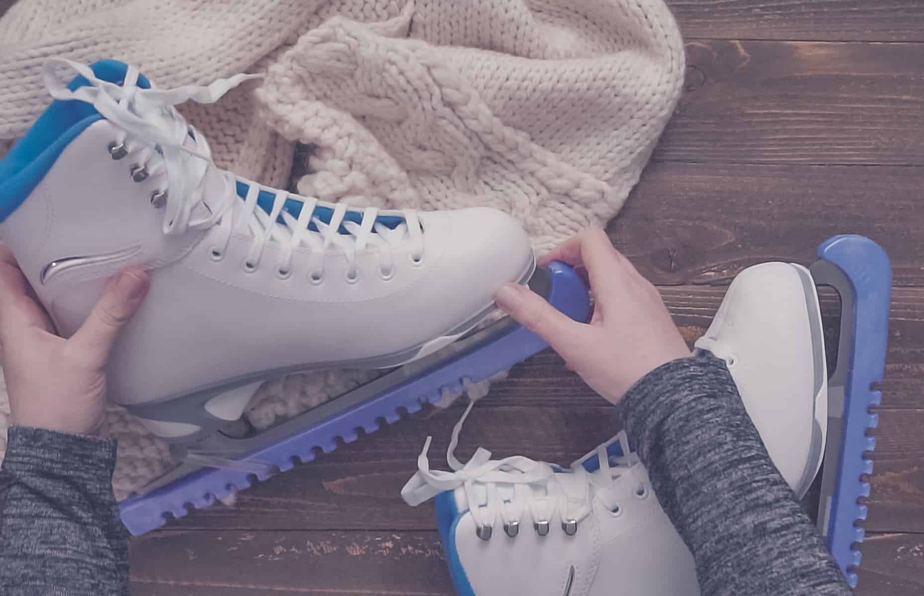 A woman puts blue blade guards on white figure skates as she prepares to donate them, no longer needing them herself.