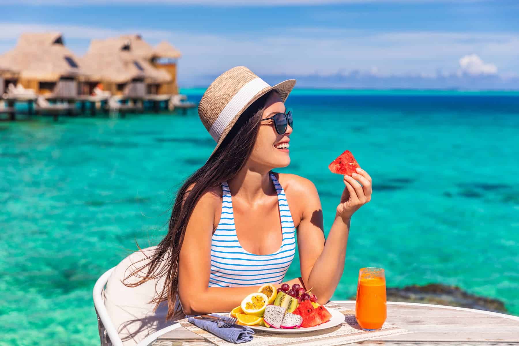 Luxury resort vacation woman eating fruits on beach hotel room with private terrace.