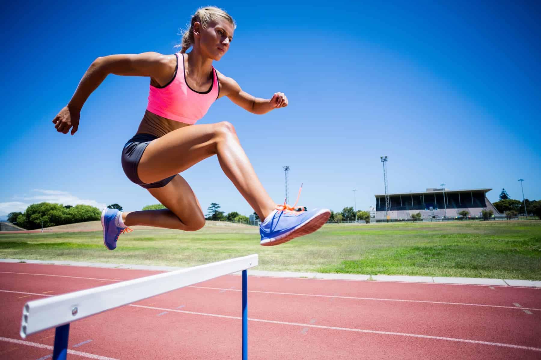 Athletic female runner jump over a hurdle because she won't let anything stop her goal setting plans. 