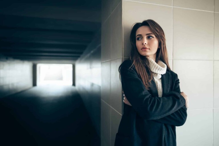 A young woman stands alone in a subway tunnel, grappling with the fear of rejection, a common struggle for highly sensitive people.