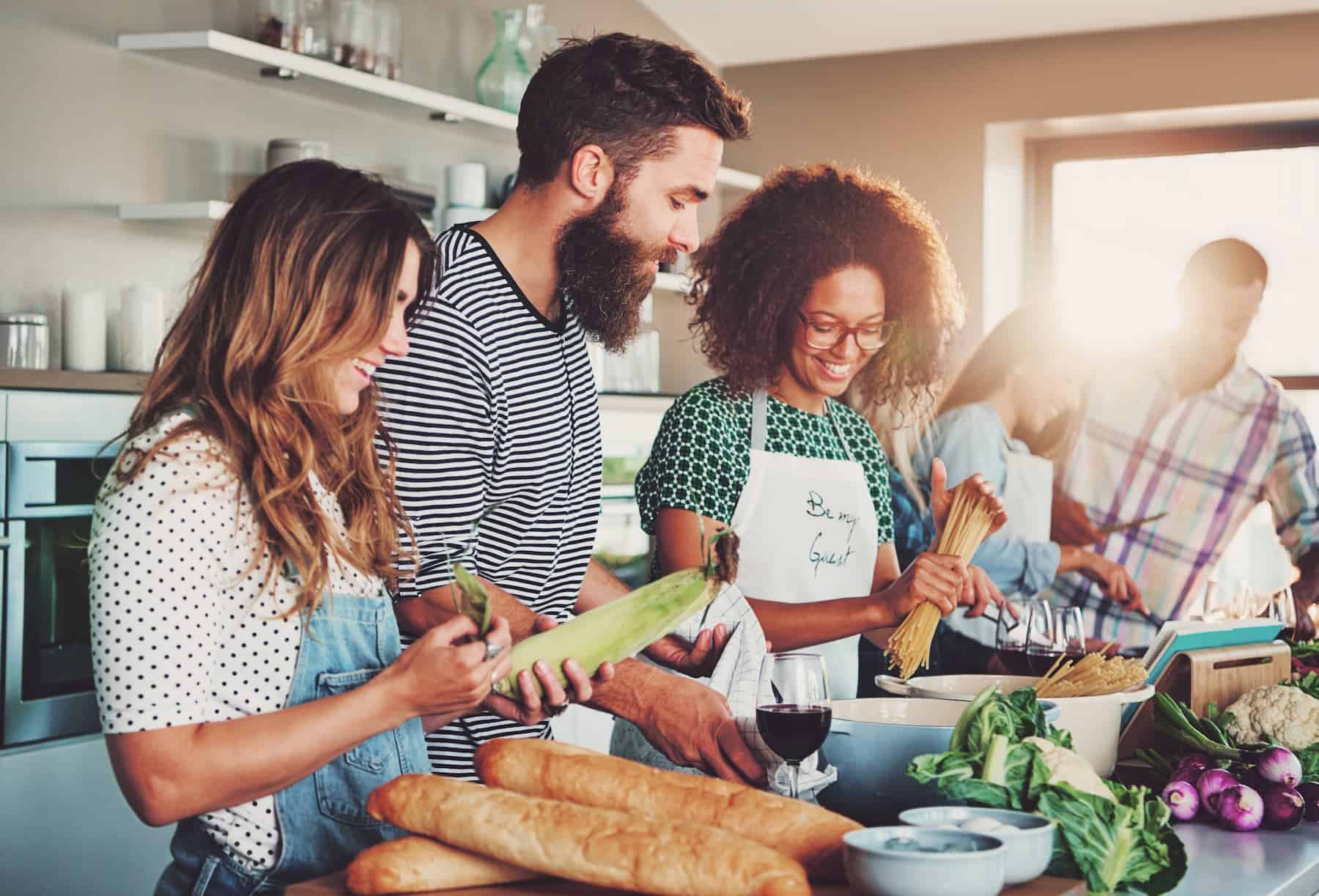 People are enjoying a social gathering while preparing meals at a cooking class.