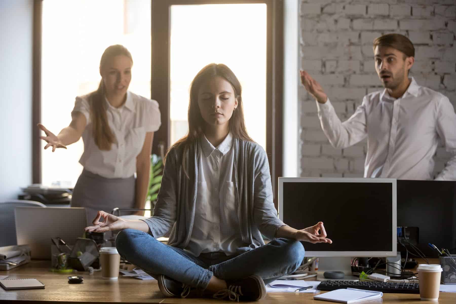 Young woman meditating at workplace as a coping strategy for feeling overwhelmed.