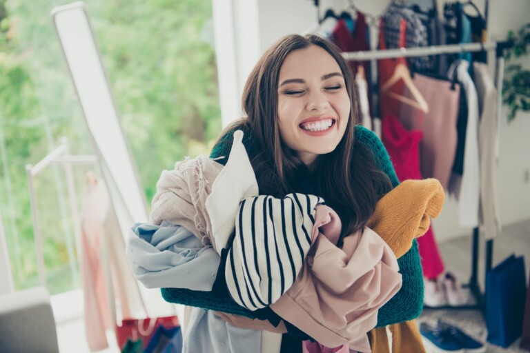 A happy young woman hugs her clothes tightly because she can't let go of her possessions.