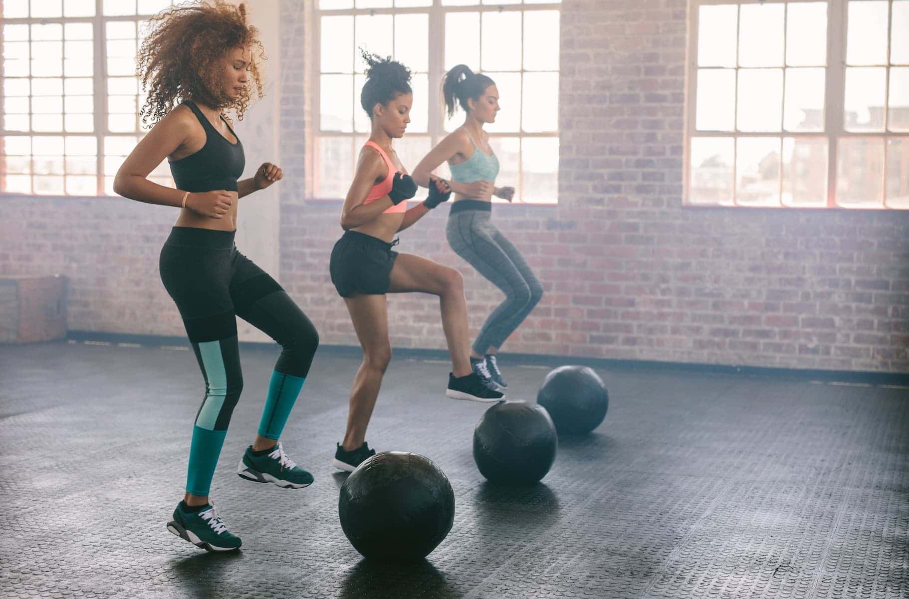 Women are exercising in an aerobics class using medicine balls on the floor to reduce stress in their daily lives.