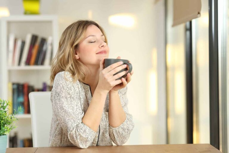 In her serene home, a young woman sits comfortably on a modern chair, enjoying a moment of relaxation in her home adorned with minimalist furnishings, all chosen with the intention of nurturing her mental health.