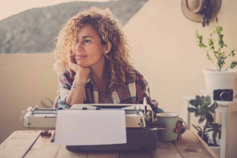 Woman with blonde curly hair taking a break from writing her novel. Writing is one of the best jobs highly sensitive people.