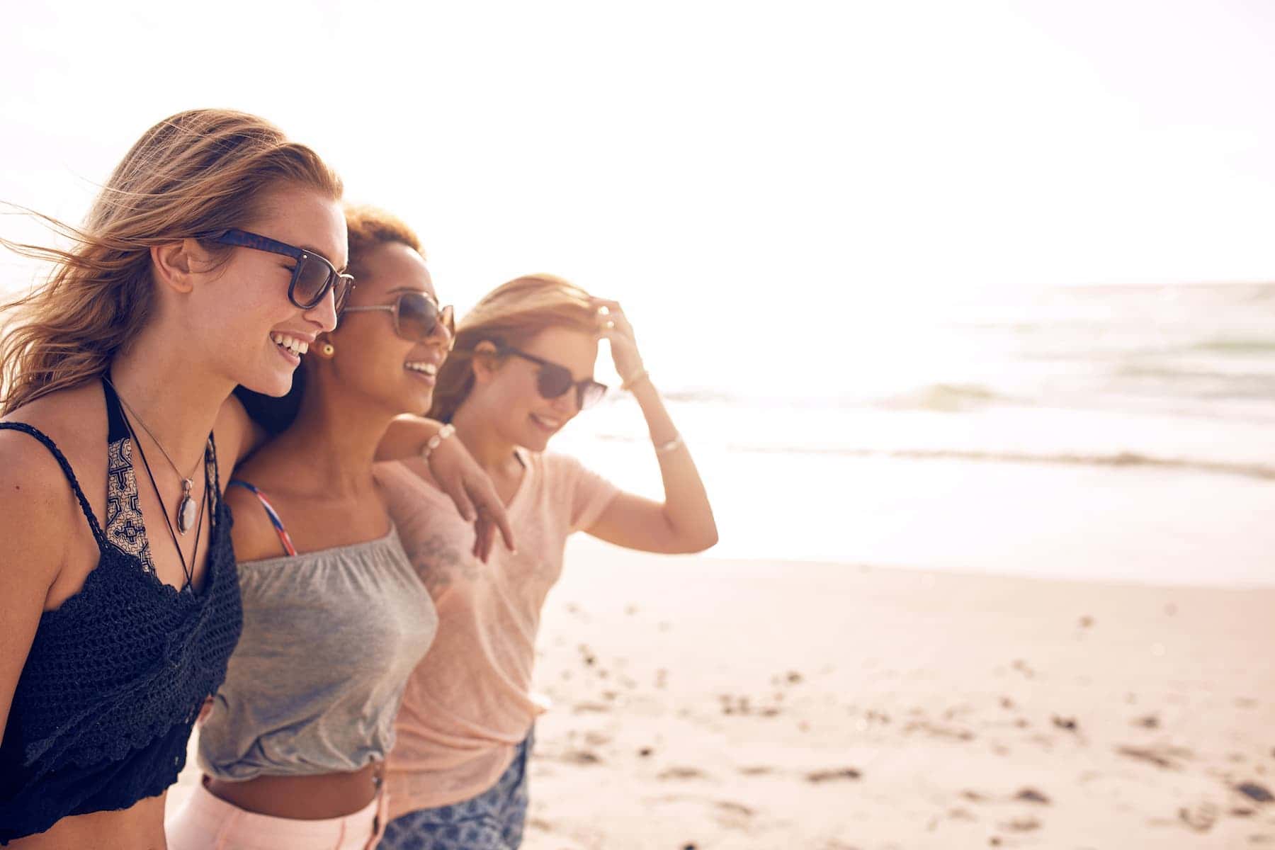 On the beach, three women—an HSP, an introvert, and an empath—walk side by side, each embodying their distinct personalities.