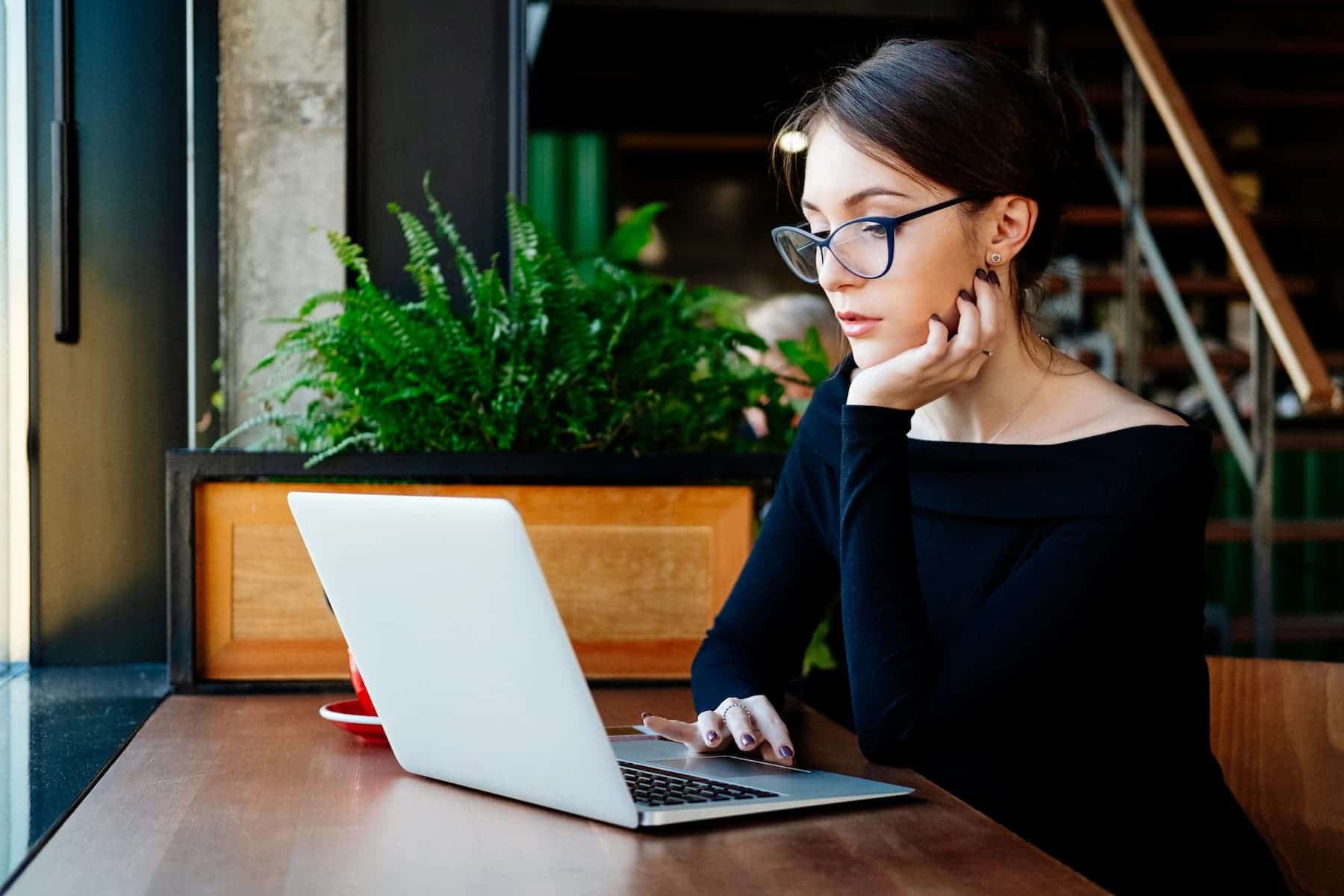 Sitting at her desk, a young woman with glasses works on strategies to overcome mediocrity.