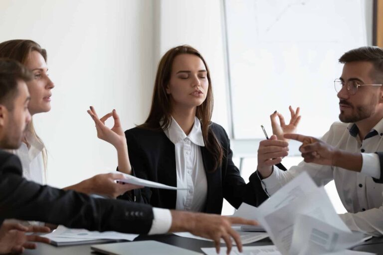A mindful young businesswoman meditates at work, using it as a stress-busting technique to include in her daily relaxation routine.