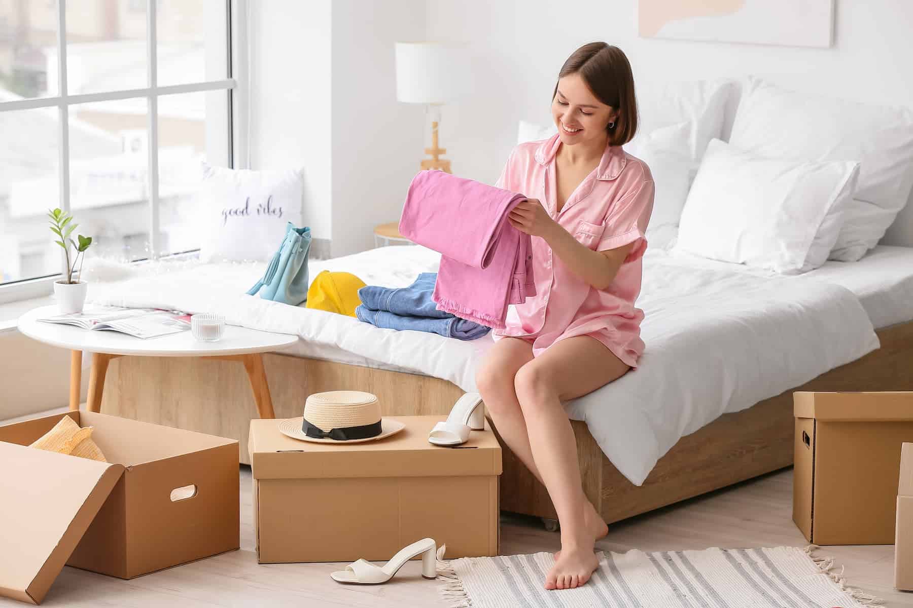 Young woman organizing clothes in her bedroom to support mental health.