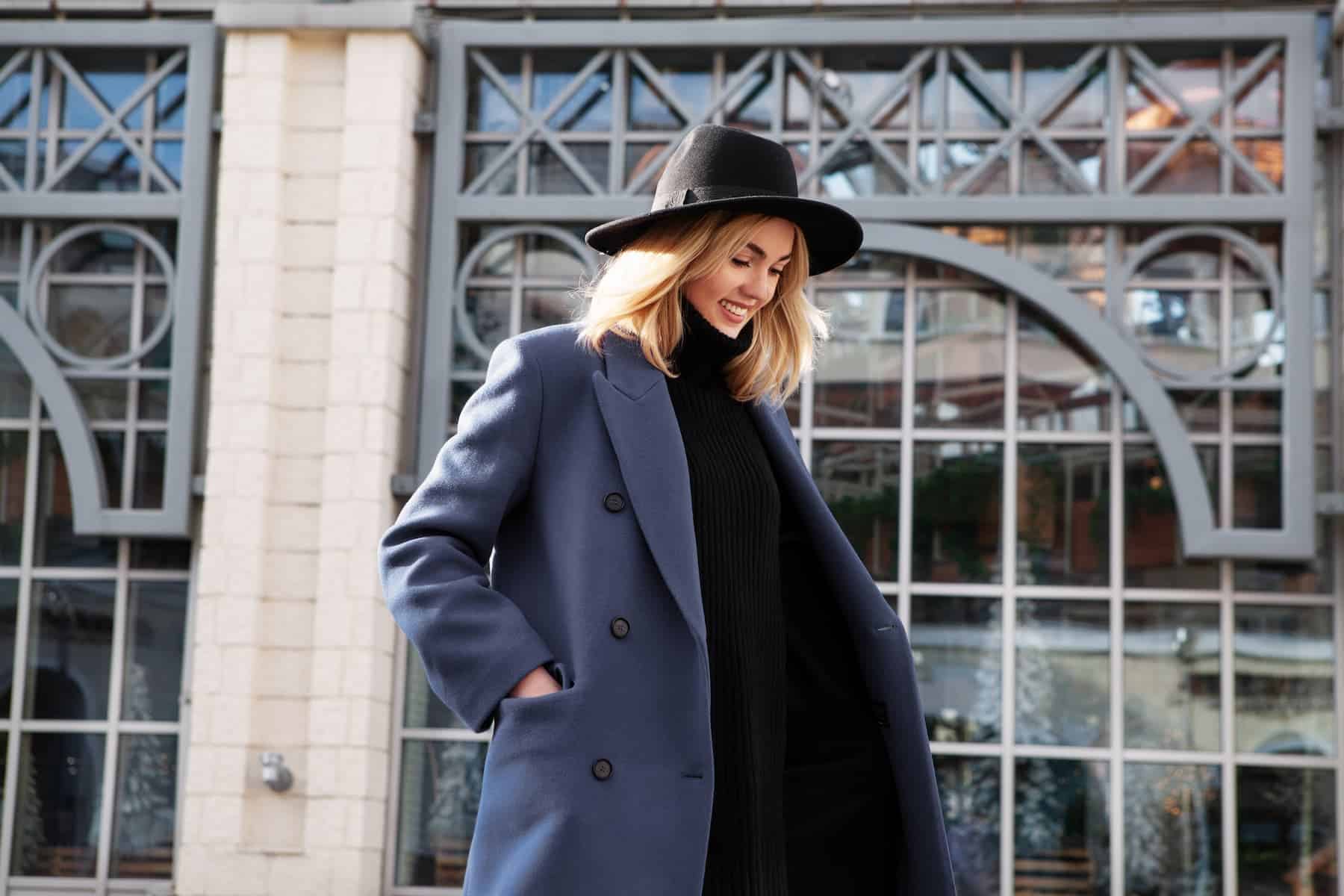 A stylish, highly sensitive woman in an autumn outfit, featuring a felt hat, gray wool coat, and turtleneck, enjoys a carefree moment, having embraced her decision not to have kids.