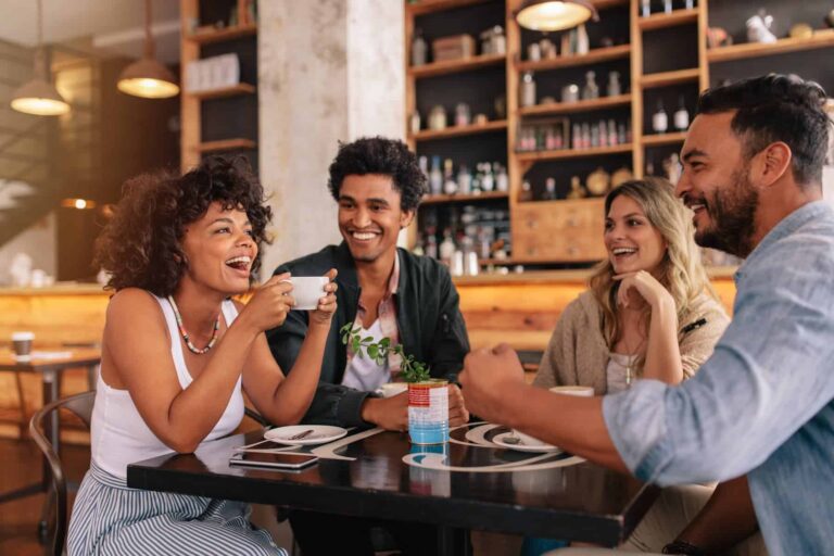An extroverted woman laughs joyfully with her friends as they enjoy their time together at a café.