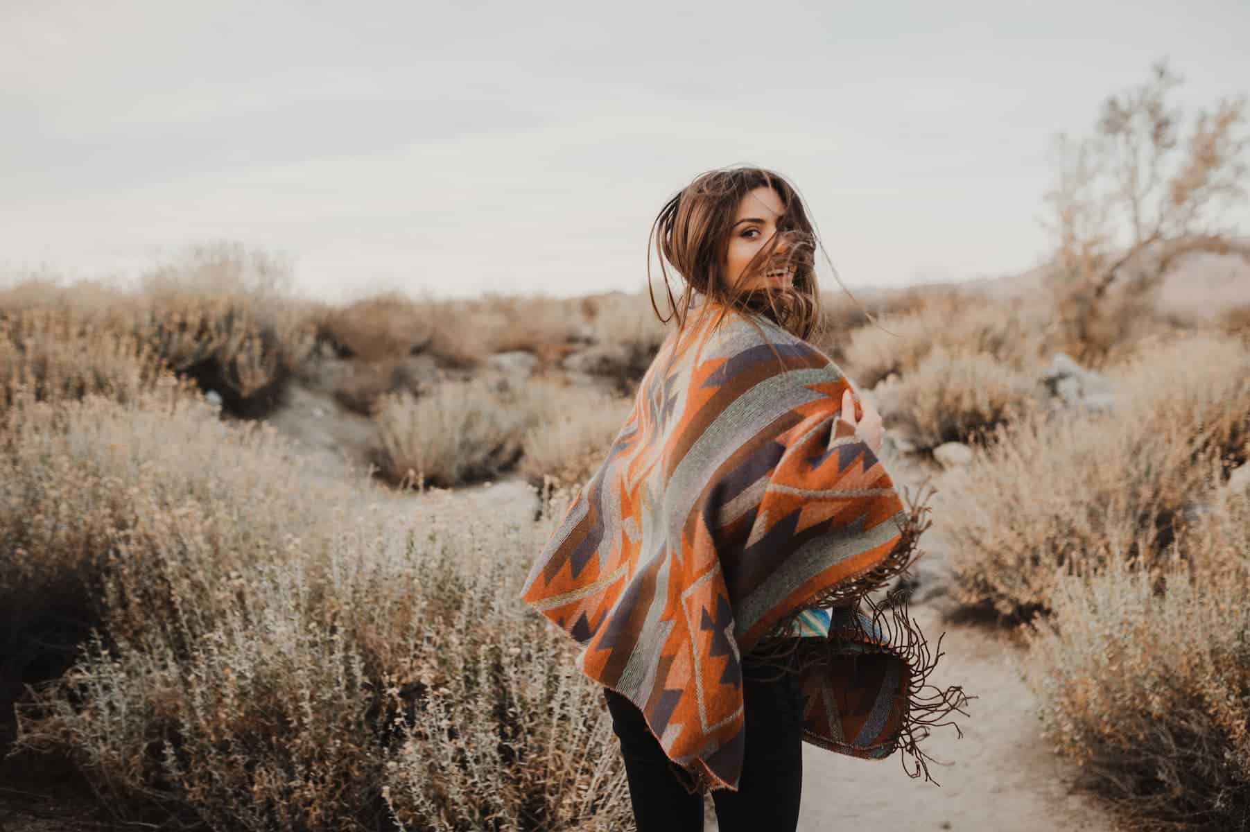 A hipster girl enjoys the desert, fully embracing the moment, her empath signs showing in how deeply she connects with her surroundings.