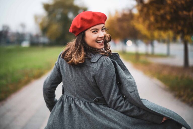 Happy and thriving as an extrovert, a highly sensitive woman in trendy clothing walks down the street, smiling with confidence.