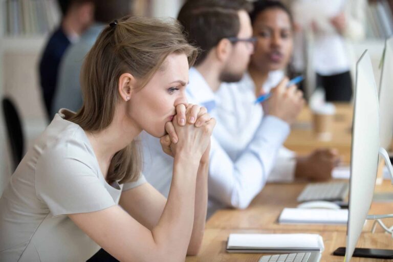 Woman sitting at her desk looking thoughtful and distant, questioning whether settling into a comfort zone is the right choice.