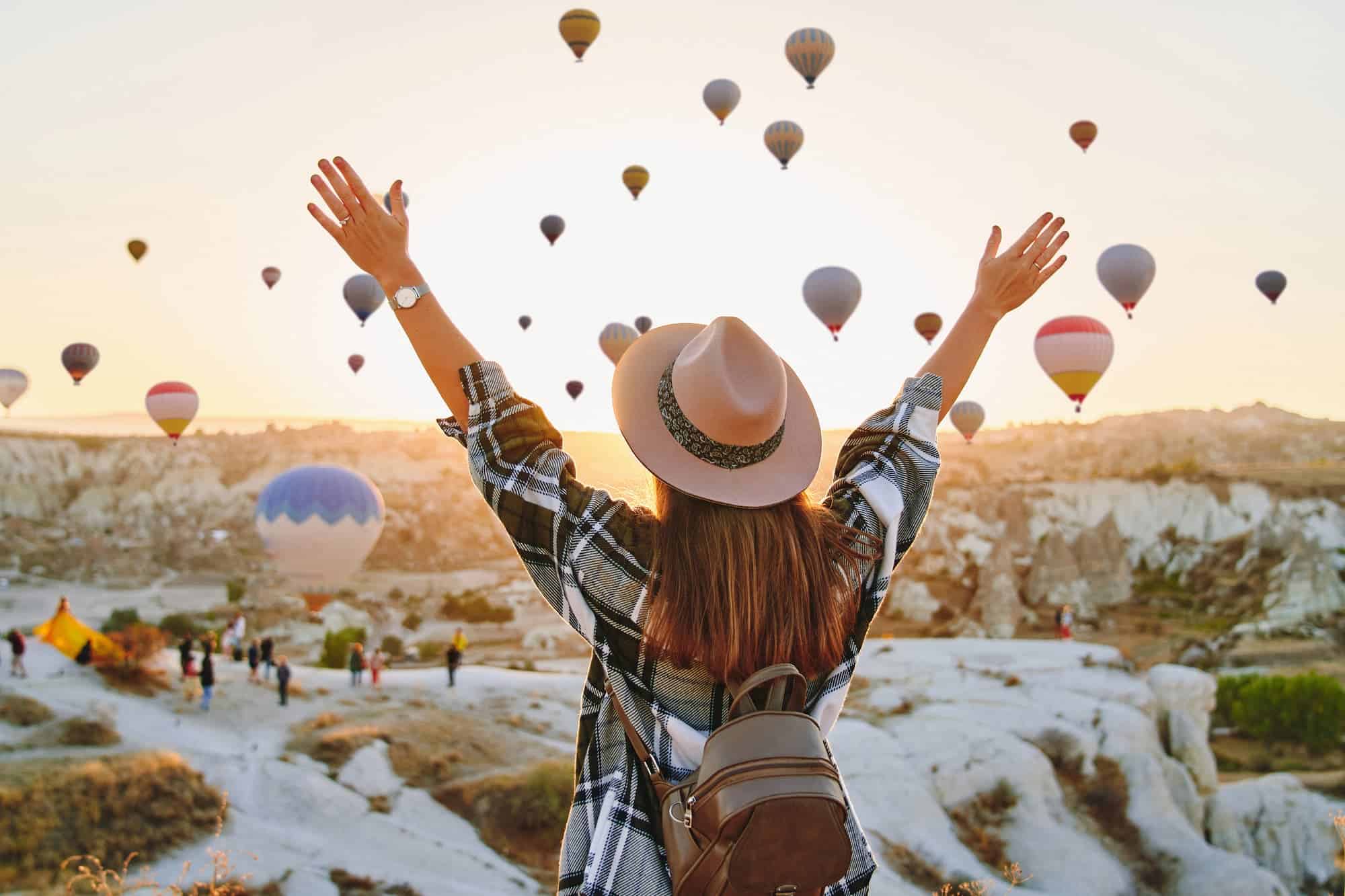 A woman in a hat and flannel faces floating hot air balloons, evoking wonder and curiosity about what is quantum physics.