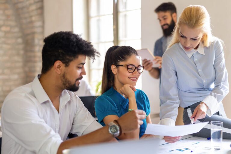 A young woman smiles at work as her boss critiques her work, viewing it as a learning opportunity through her growth mindset practice.