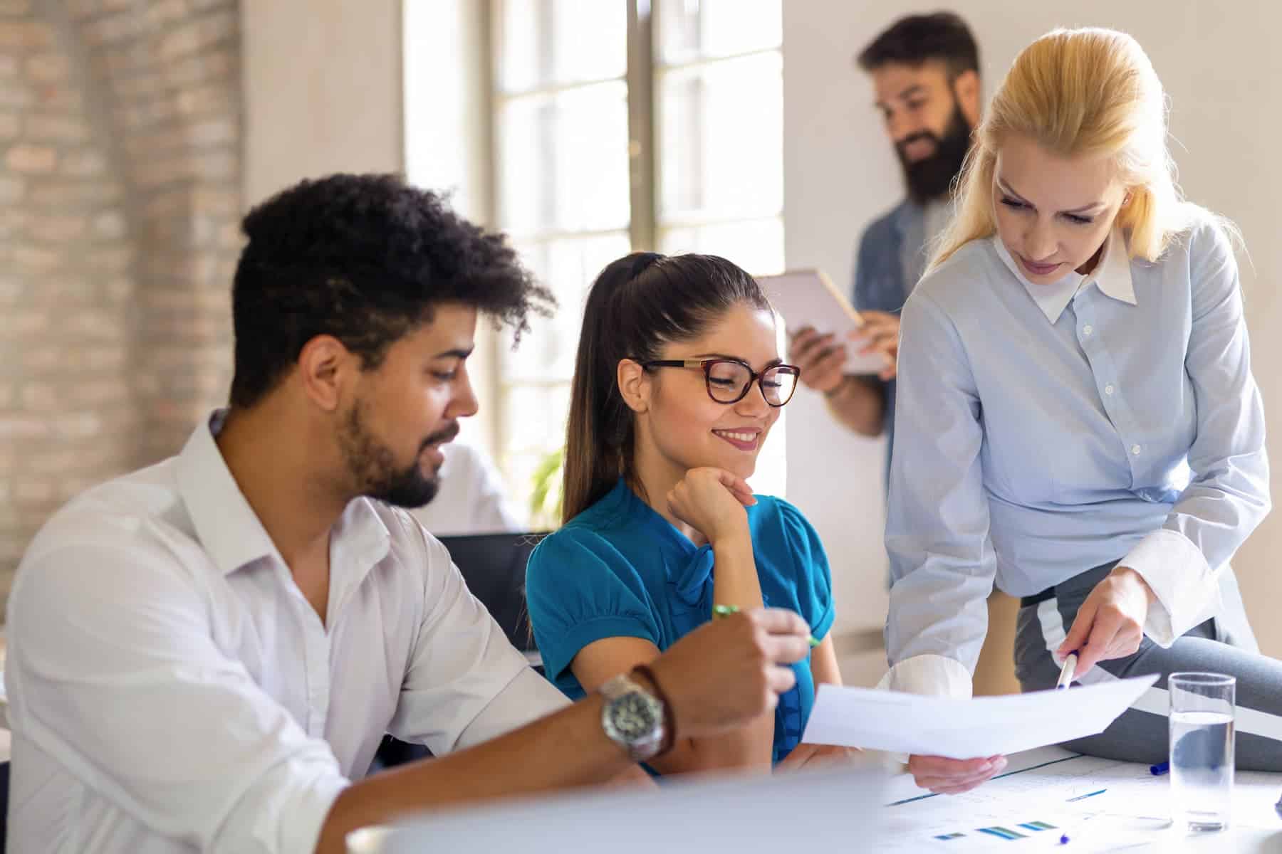A young woman smiles at work as her boss critiques her work, viewing it as a learning opportunity through her growth mindset practice.
