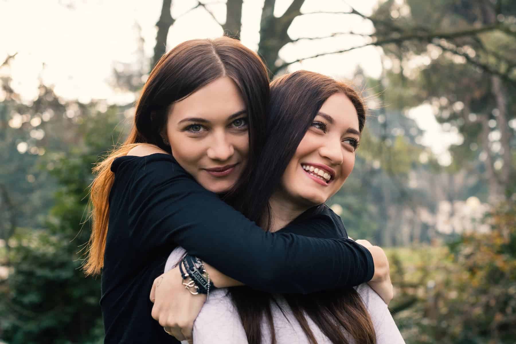 Two sisters embraces in a forested setting, reflecting the bond and balance often seen between extrovert and introvert personalities.