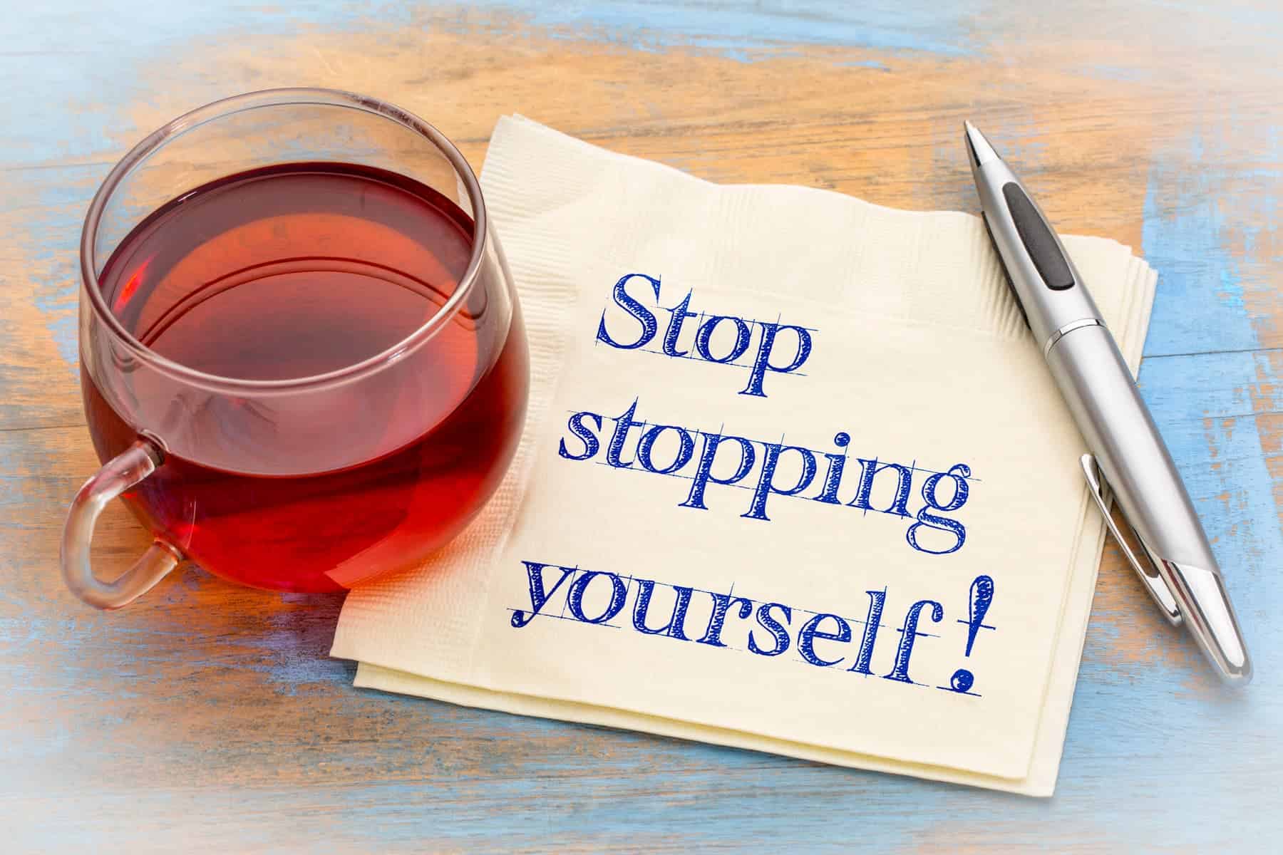 A handwritten note saying “Stop stopping yourself!” beside a warm cup of tea is a simple growth mindset example of choosing encouragement over self-doubt.