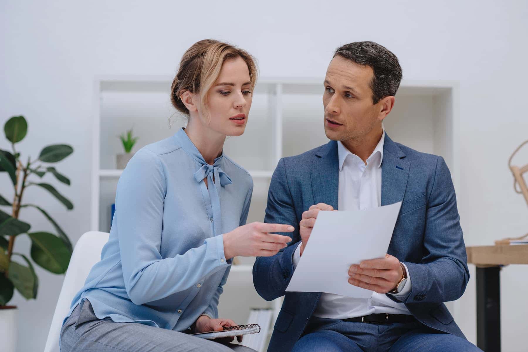 A manager giving feedback to a colleague in a bright office, demonstrating learning and development, which is the ultimate guide to growth mindset.