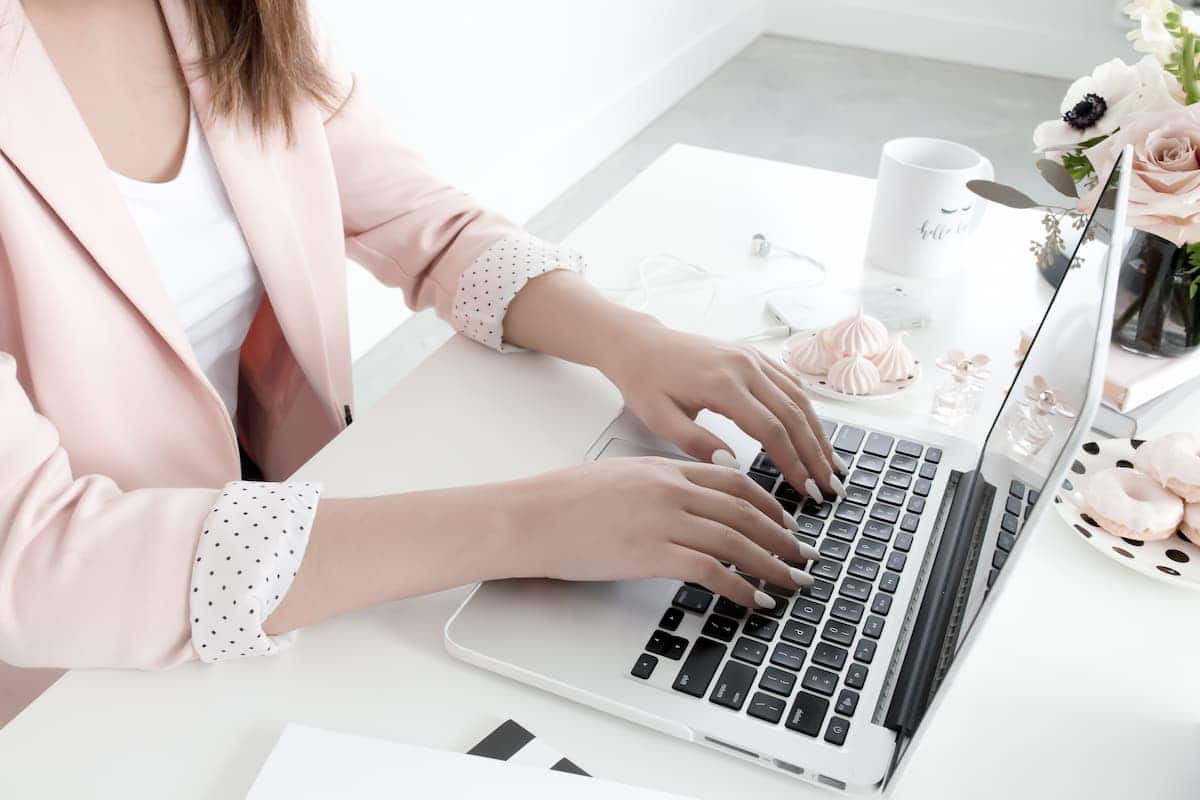 A woman types on a laptop at a desk, immersed in a quiet moment of productivity and focused flow.