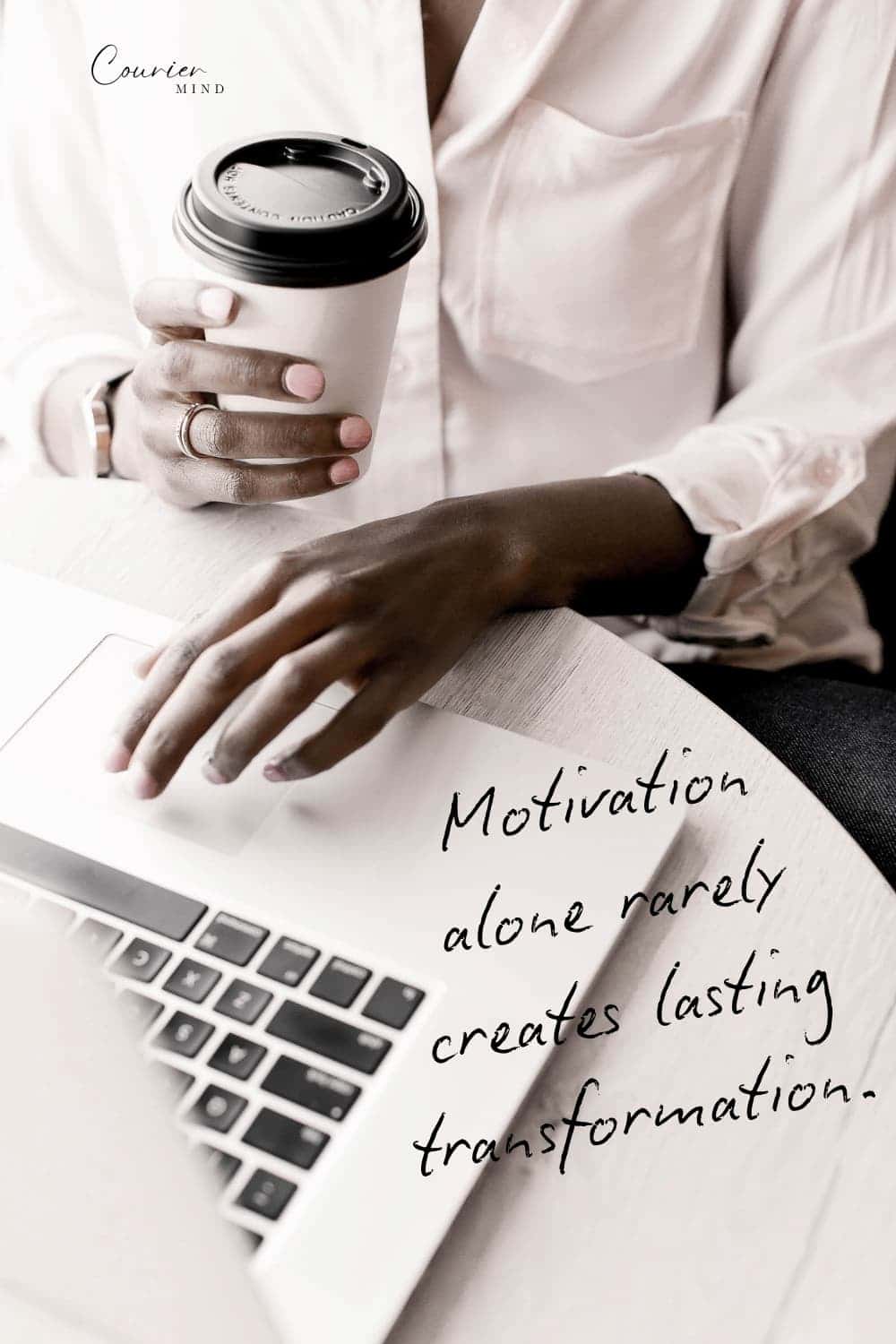 Woman working on a laptop while holding a coffee cup during a normal workday.