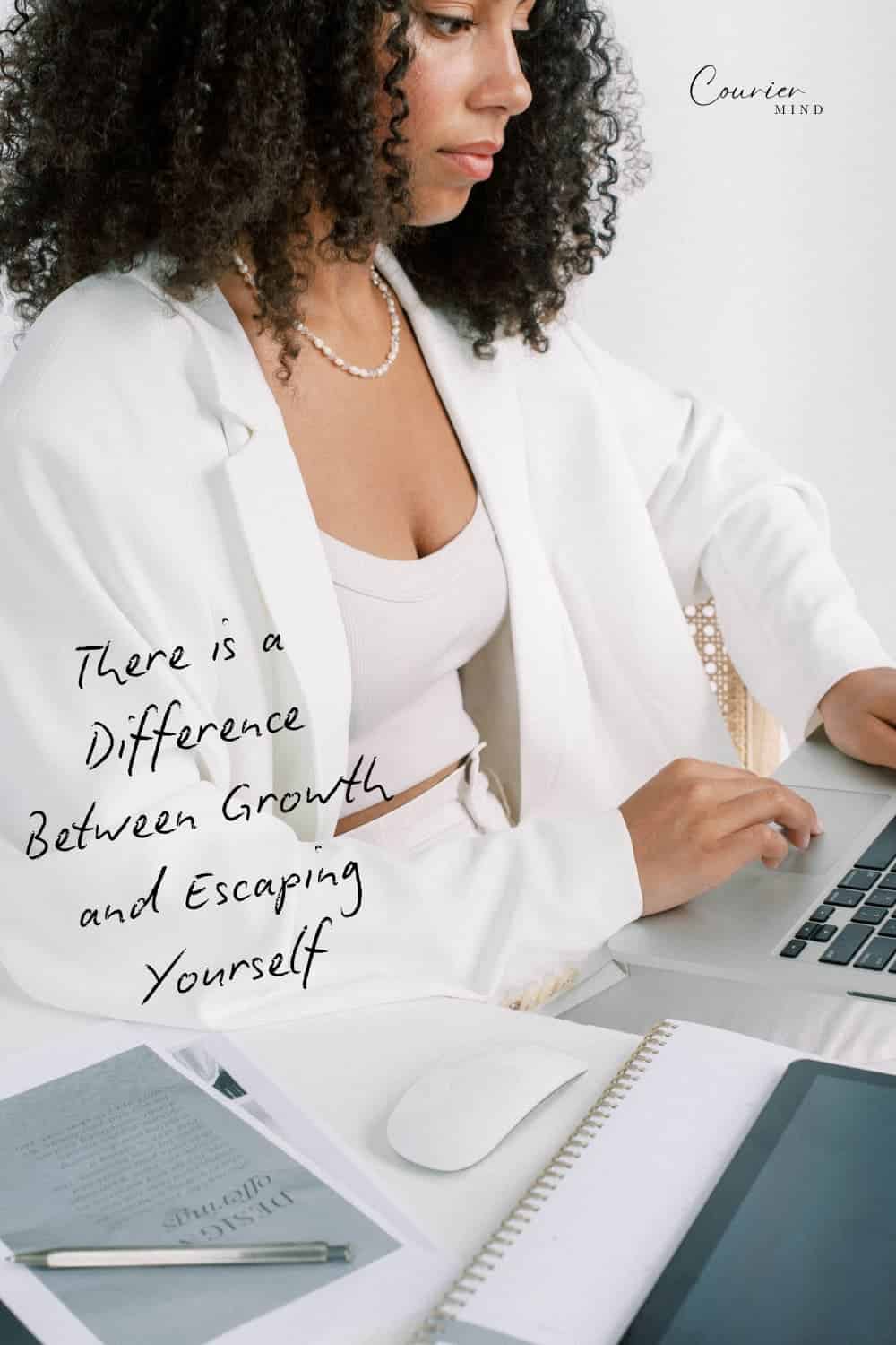 A woman wearing a white blazer and pearl necklace types on a laptop at a desk with a mouse, notebook, and papers.