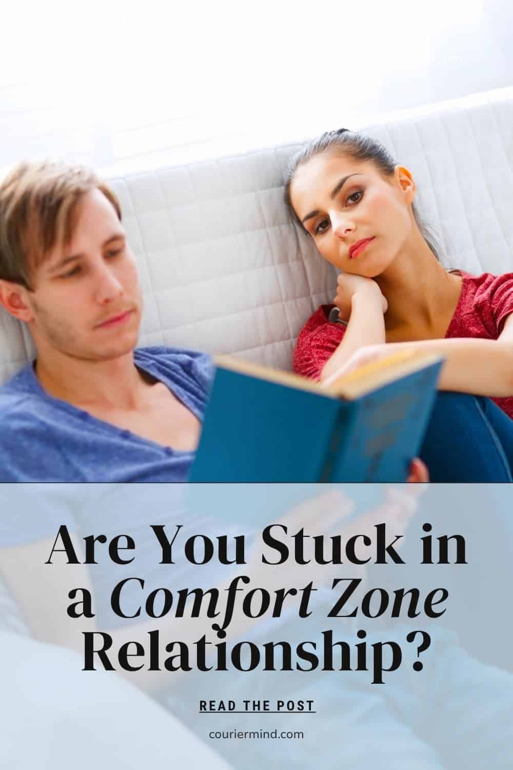 A man reads a blue book while a woman rests her head on her hand with a bored expression on a couch.