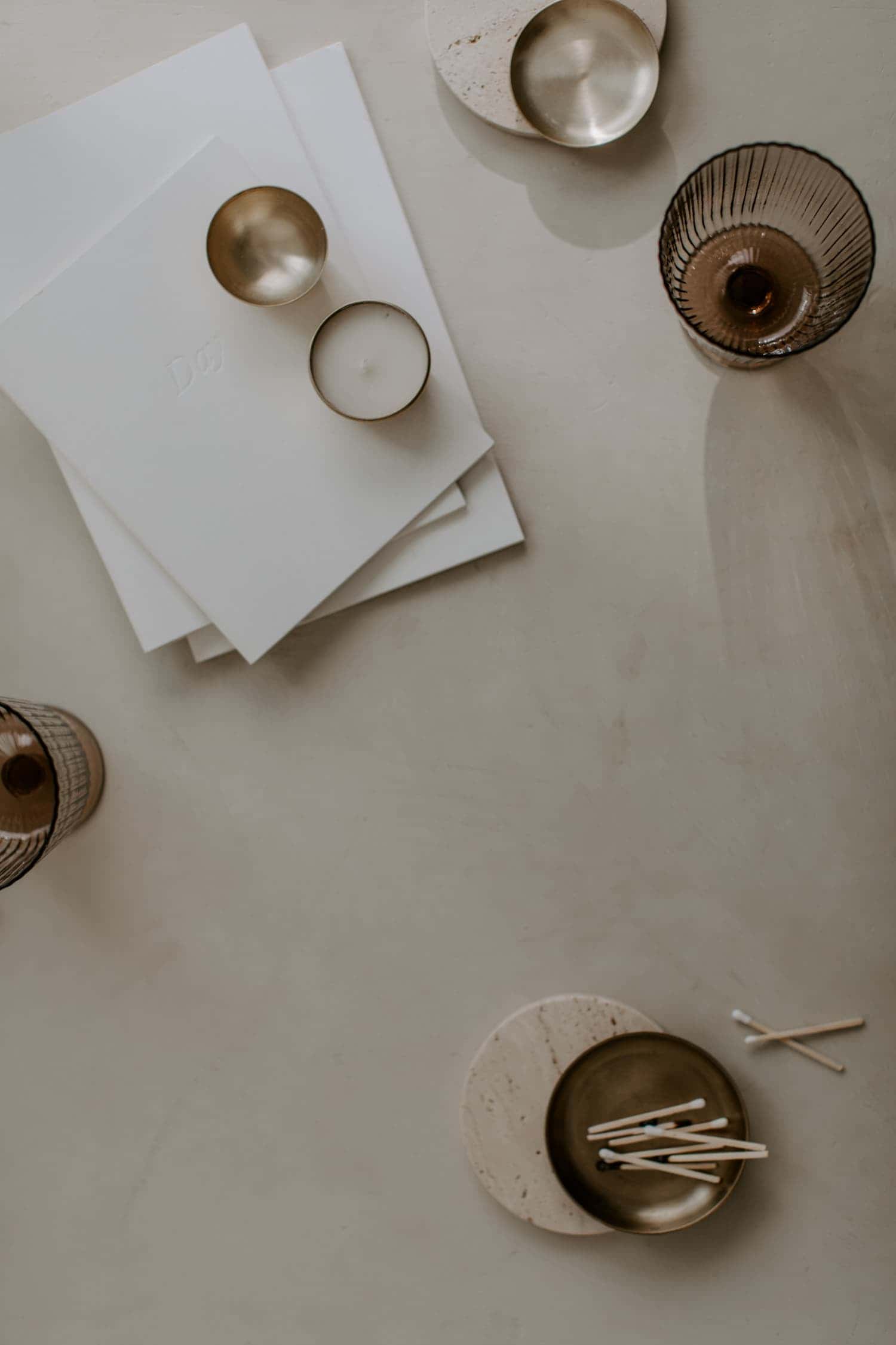 A messy creative's flatlay of little bowls, notebooks, matches, and cups.