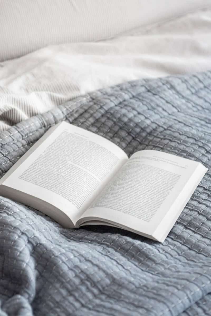 Book on a blue blanket on a bed.