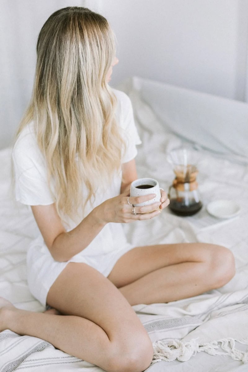 Woman enjoying coffee in bed.